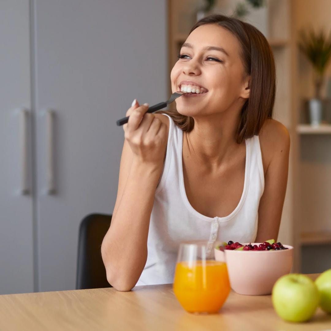 Mulher tomando café da manhã com frutas e suco